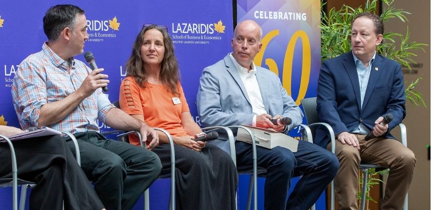 David Wheatley speaks into the microphone as other panellists look on