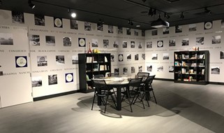 A gallery with book shelves and table, rows of photographs on the walls