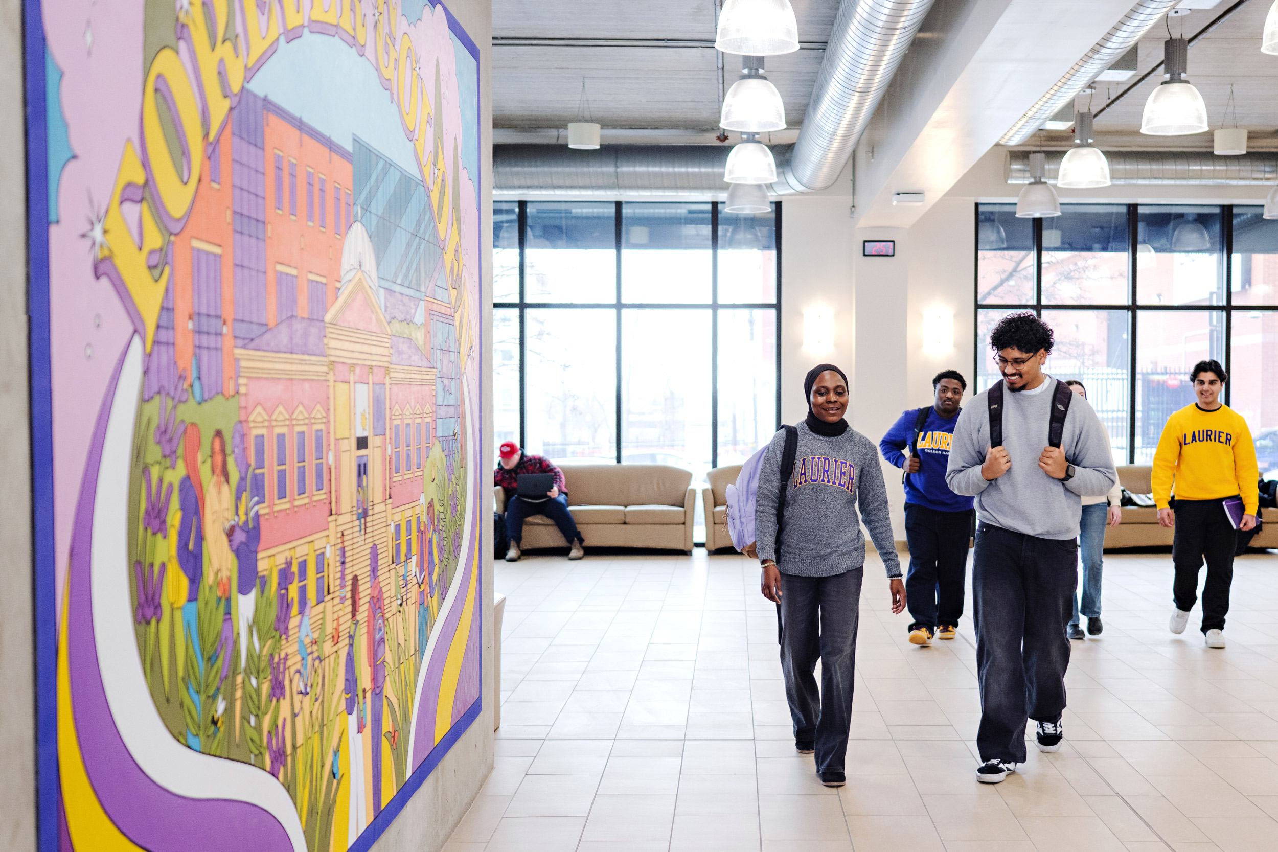 Students walking inside the RAC building with a mural on the left