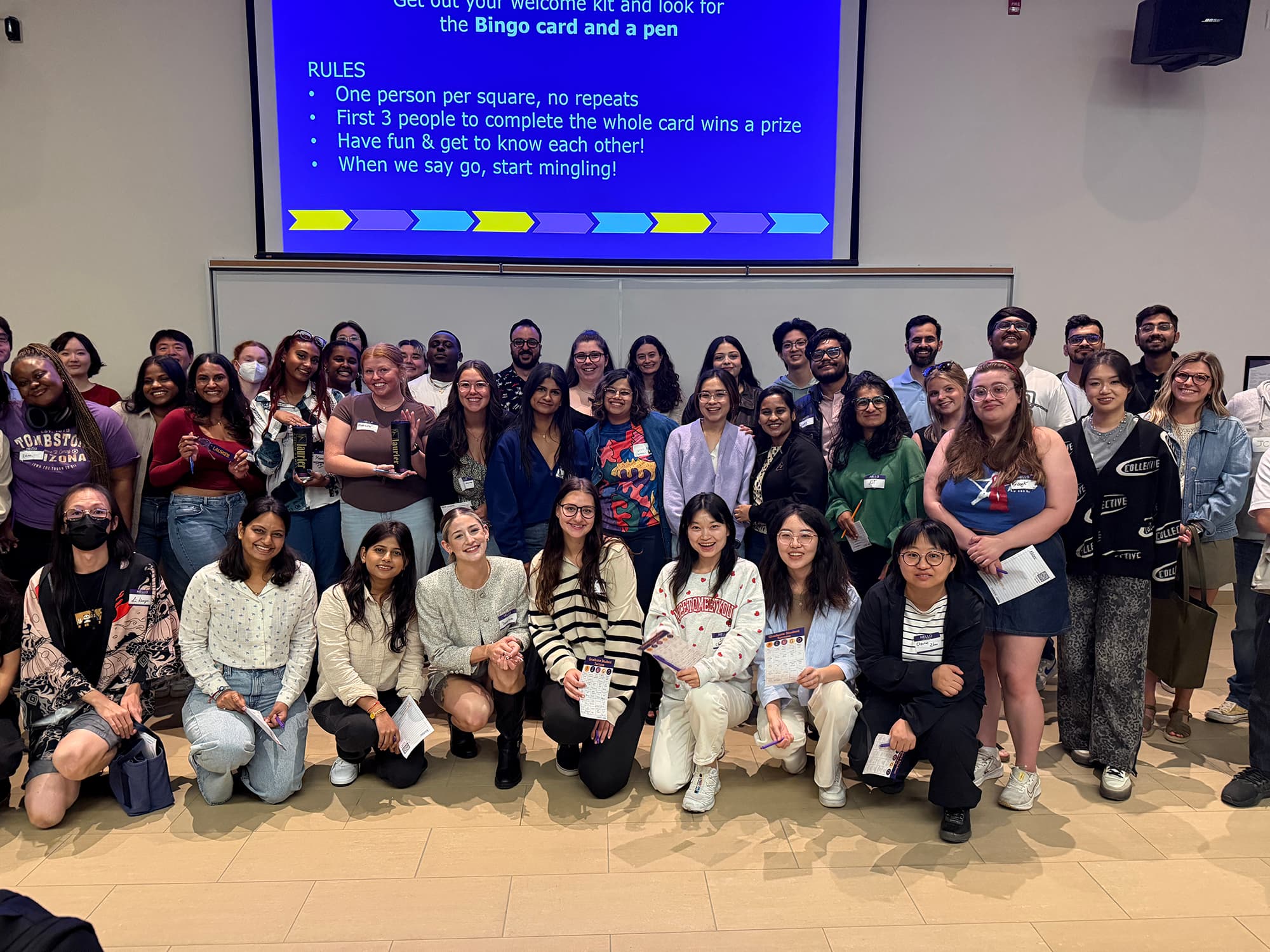 A group of students posing in a group shot with their bingo cards