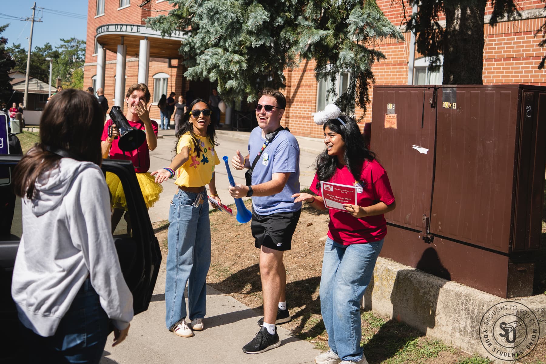 Student volunteers welcoming a student outside a residence during move-in