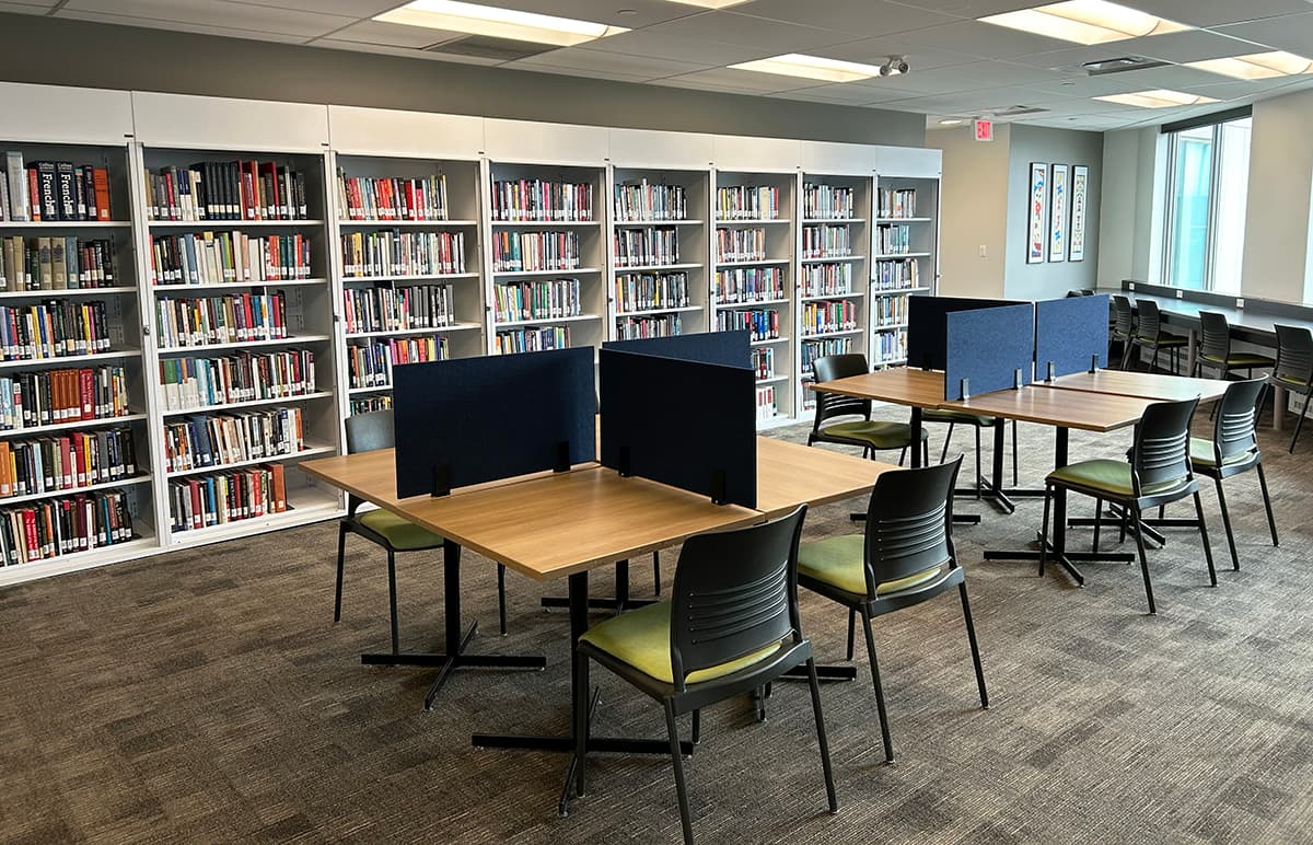 Desk seating with dividers and a wall of bookshelves in the background