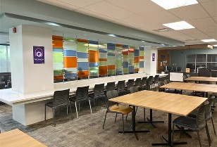 Long table between two pillars with colour glass in between, beside large tables in the centre of an aisle