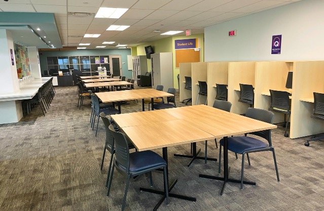 Row of large tables and cubicle desks along a wall