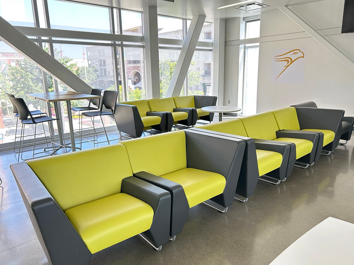 Couches, tables and desk seating in front of a large wall of windows