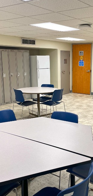 Tables in front of a row of lockers and a fridge