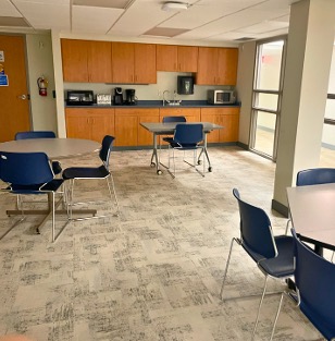 Three tables around a room with a kitchenette in the background