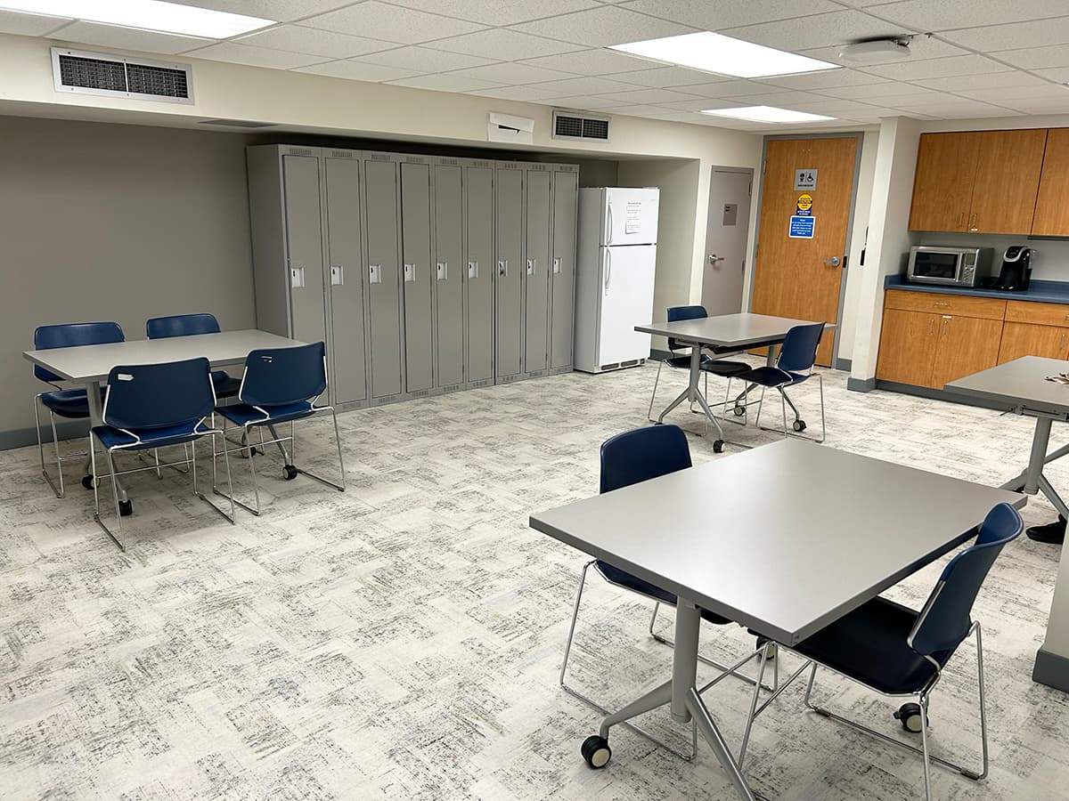 Tables in front of a row of lockers and a kitchenette