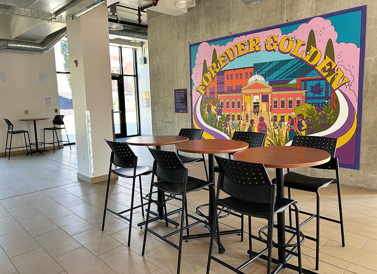 Lobby with tables and a large 'Forever Golden' mural on the back wall