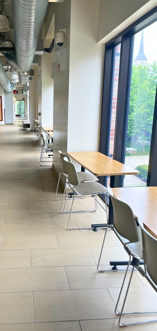 A long hallway with desks and benches up against a wall with large windows