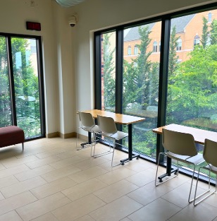 Two desks and a bench facing walls of large windows