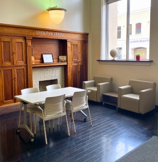 A desk and two lounge chairs next to a wooden fireplace surround
