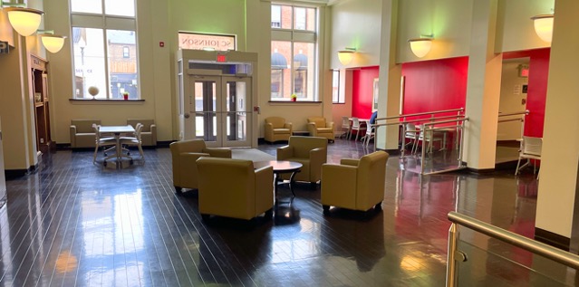 Foyer with lounge chairs surrounding a coffee table in the centre and desks and other chairs in the background