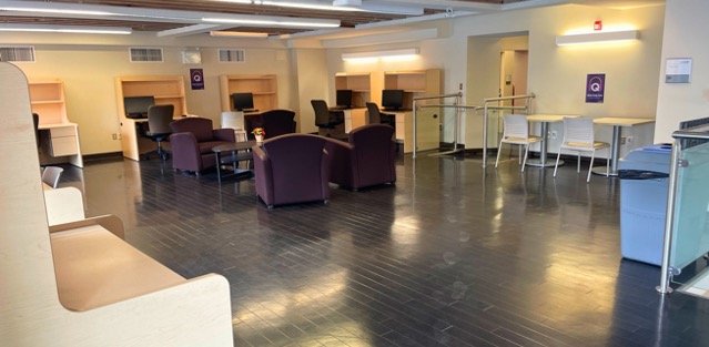 Lounge chairs surrounding a coffee table in the centre of a room with cubicle desks lining the walls