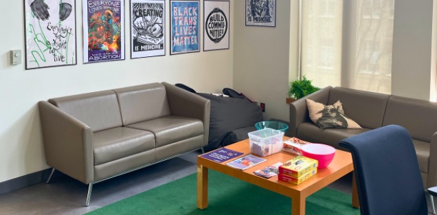 Two couches around a coffee table in front of a wall with posters