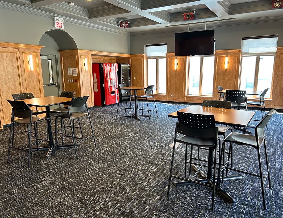 Tables in an open floor area in front of windows and vending machines in the corner