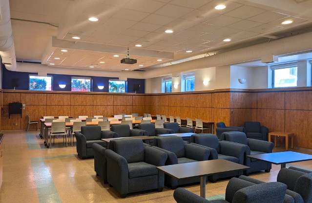 Rows of lounge chairs and tables in front of rows of desks