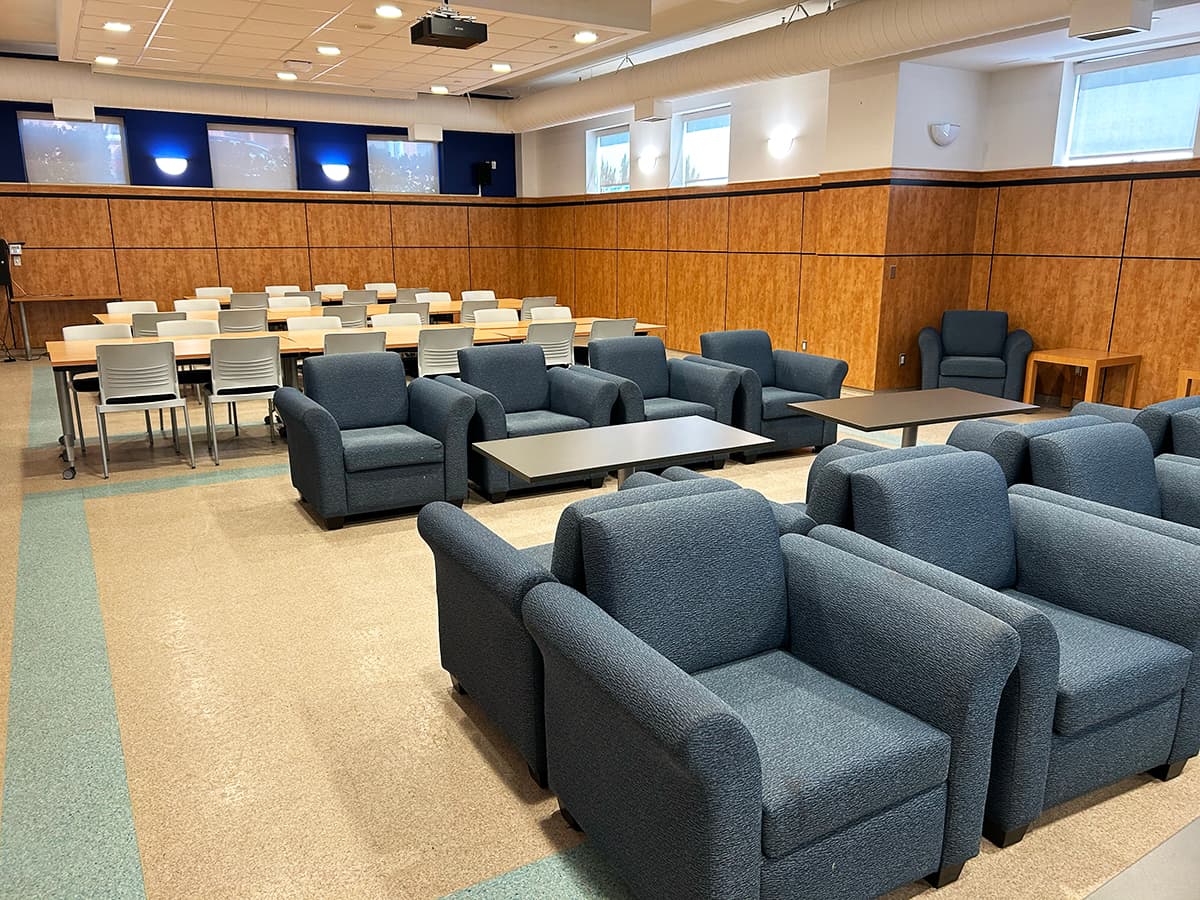 Rows of lounge chairs and tables in front of rows of desks