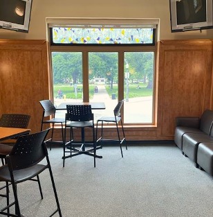 Two desks and lounge seating around a large window