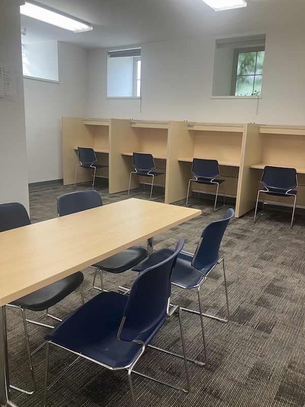 A large table in front of a row of desk cubicles along the back wall