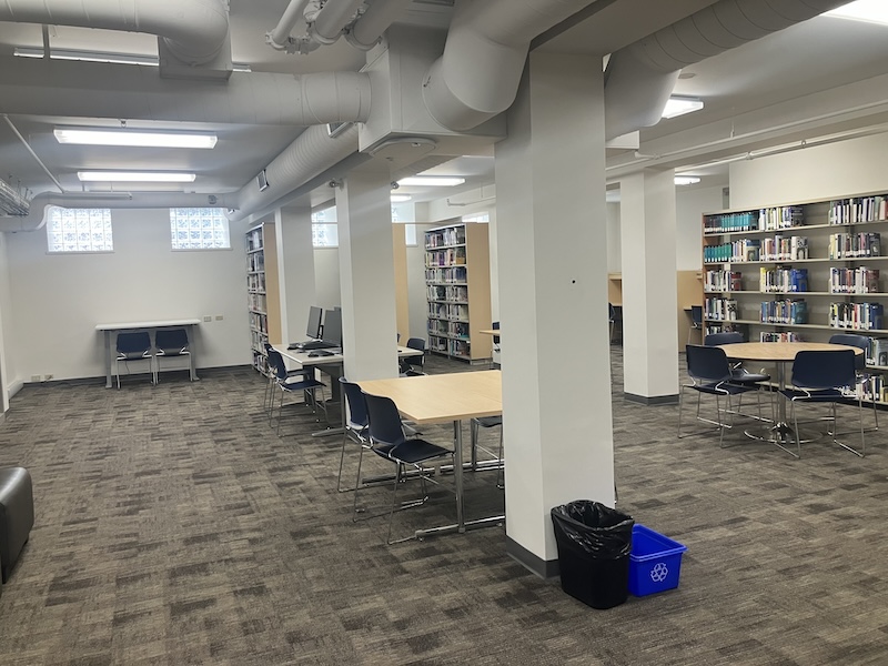 A large room with tables and bookshelves along walls and in between pillars
