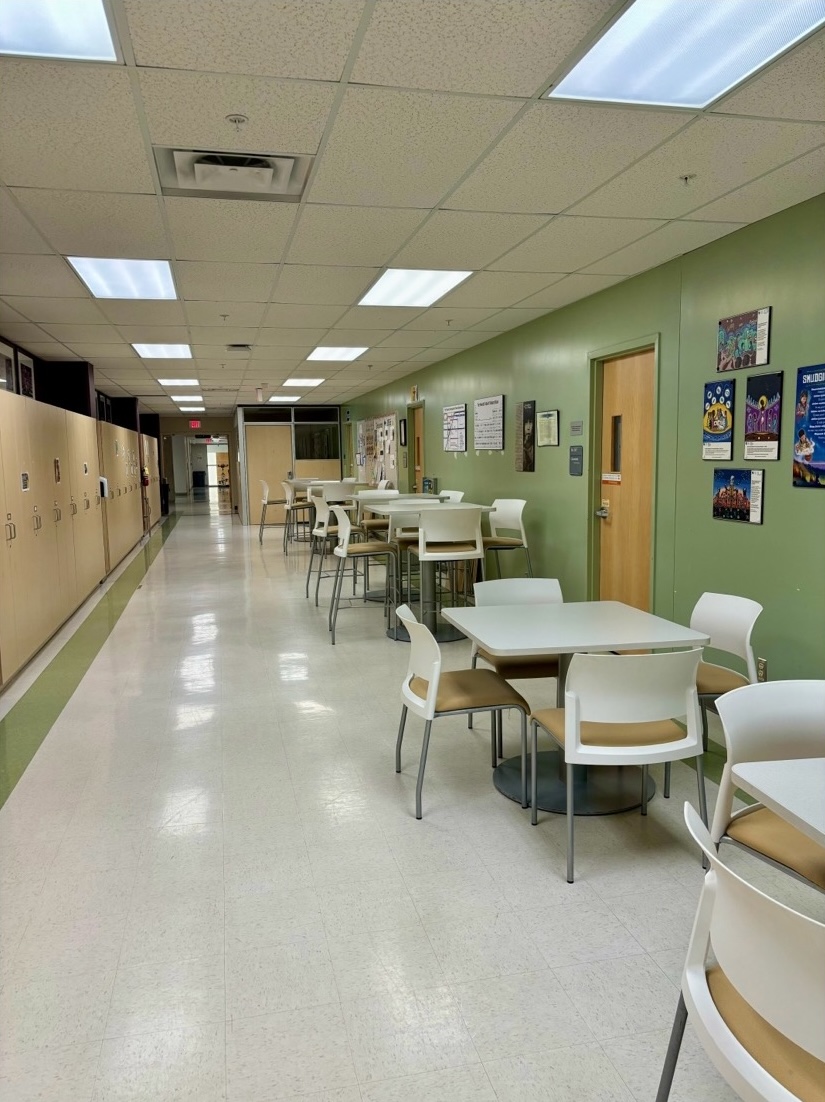 Hallway with a row of tables lining the right wall between classroom doors