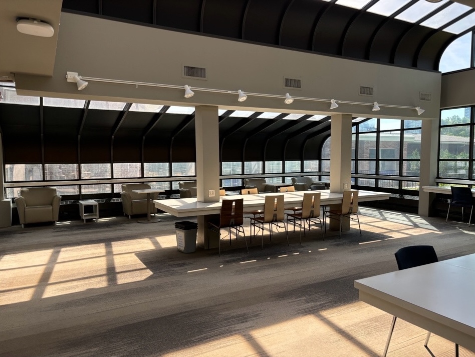 A large table surrounding pillars beside lounge chairs in front of windows