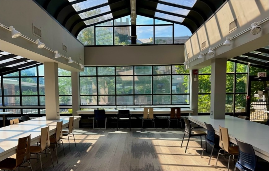 Two large tables surrounding rows of pillar in front of a long desk facing a window