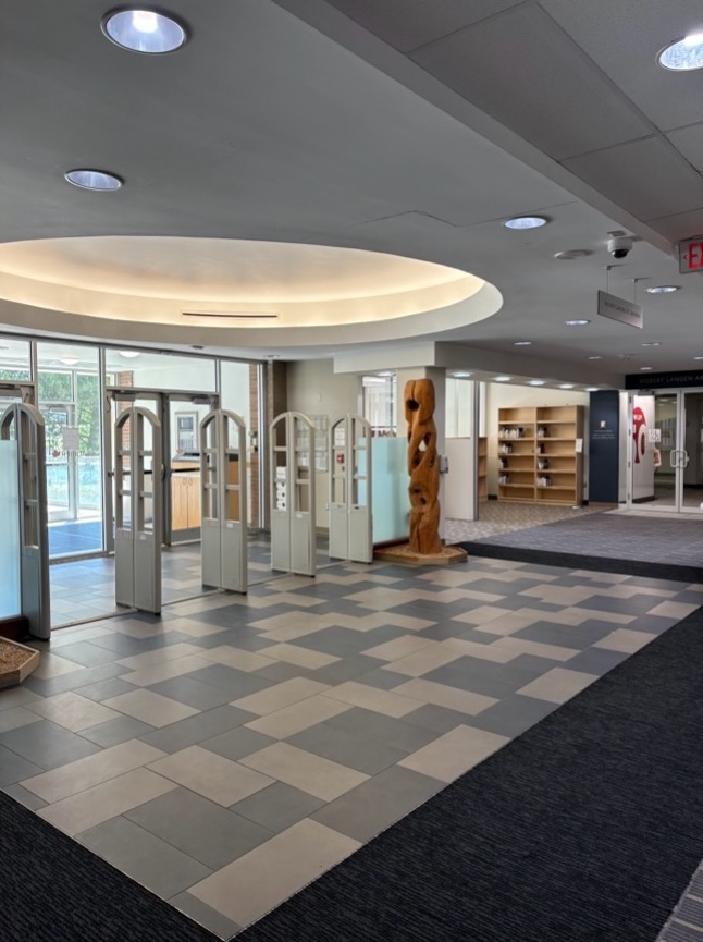 Foyer with glass doors, title floors, a wooden sculpture and bookshelves