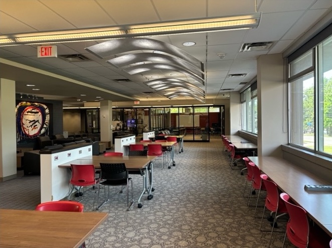 Aisle lined with desks and long tables facing out windows