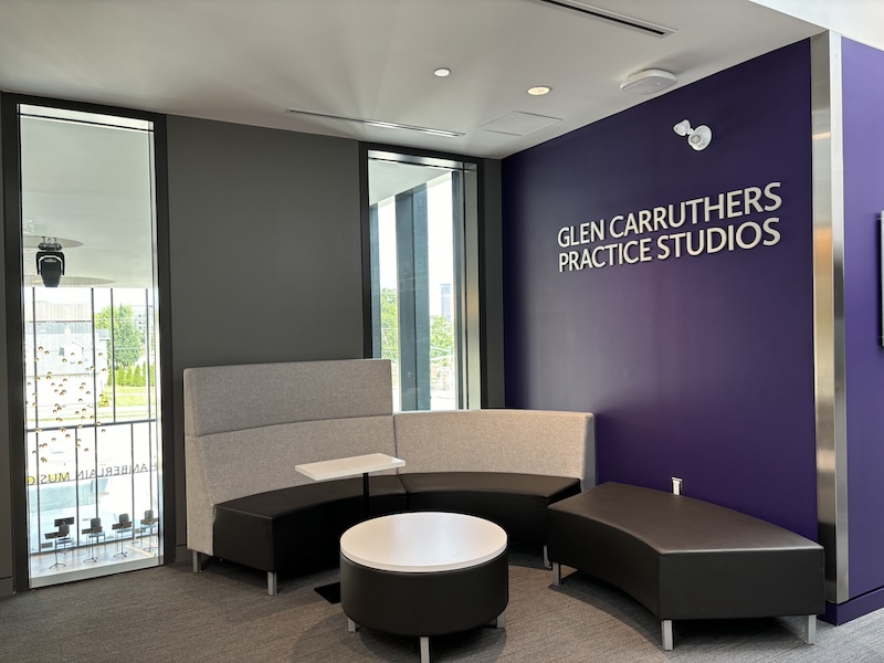 Round modular benches with a round coffee table in front of a sign that says 'Glen Carruthers Practice Studios'