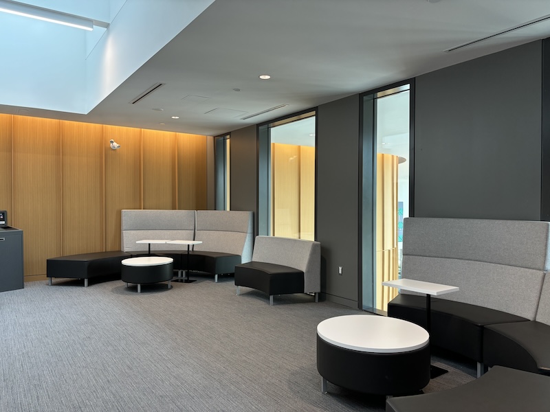 Two round modular benchs with coffee tables and side tables in front of a wall with windows