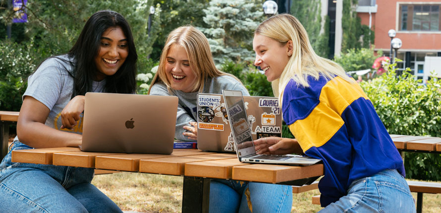 Students gather around laptops