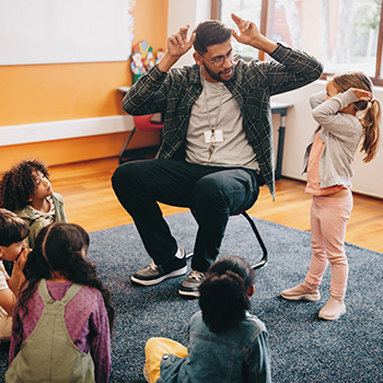 Teacher engaging with a group of young students on a carpet