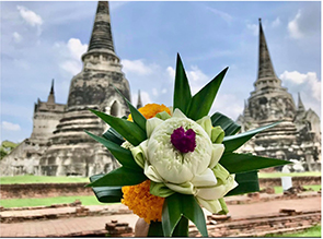 Flower arrangement help up against background of temple ruins