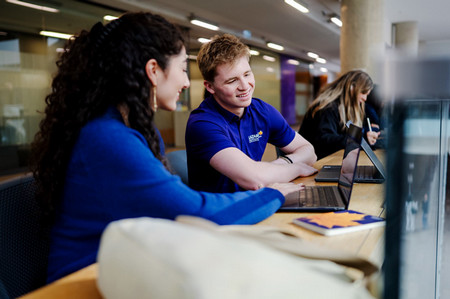 Student sitting on windowsill with skyscrapers in the background