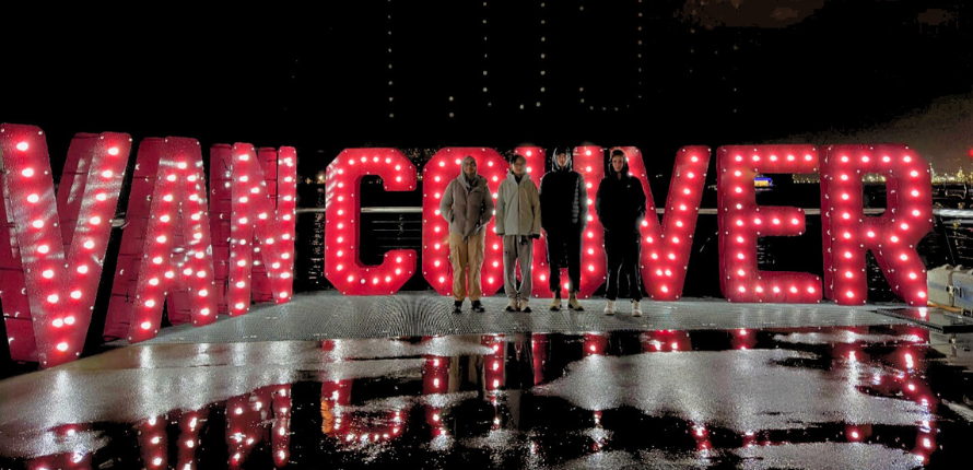 Team standing in front of Vancouver marquis letters