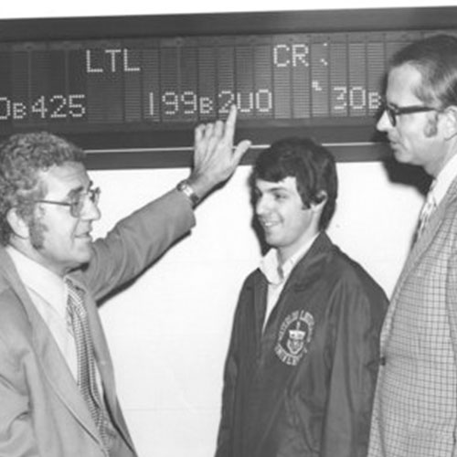 Team looking at stock market ticker (1972)