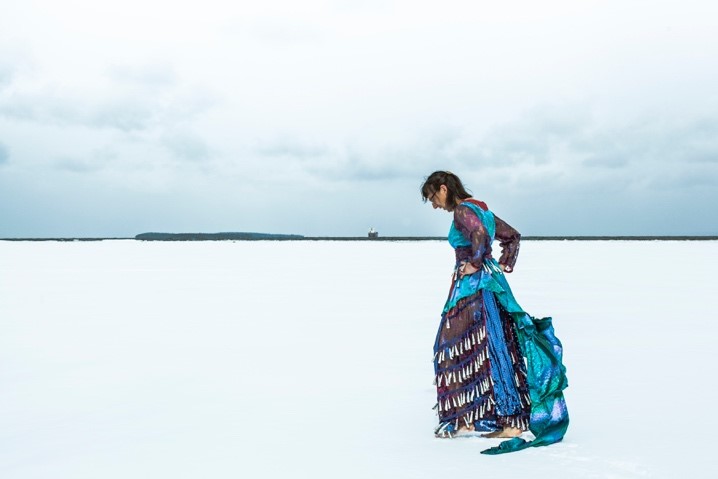 A jingle dancer, hands on hips, steps along a white plains