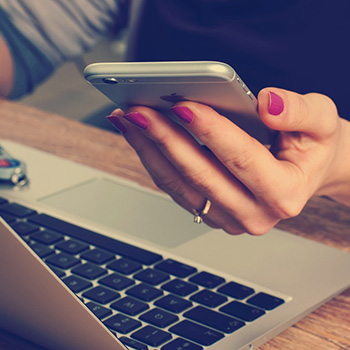 Woman using phone and laptop