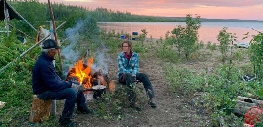 Heidi Swanson and a community partner sitting by a campfire at Decho