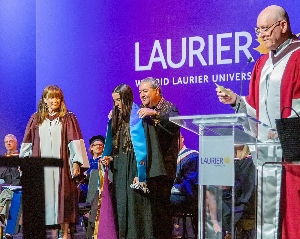An Indigenous student is hooded by Darren Thomas at Laurier Brantford convocation