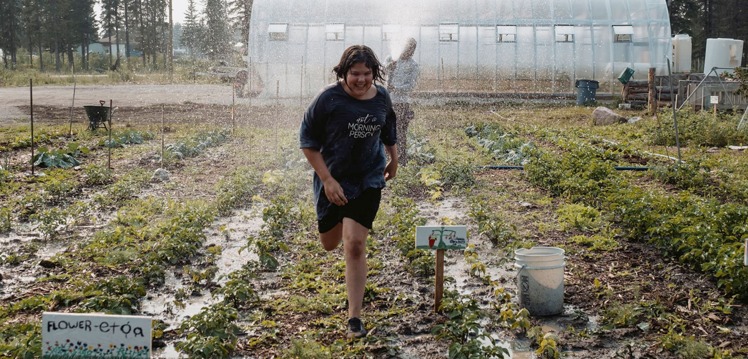 girl runs through garden hose