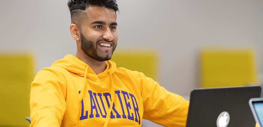 students smiling and sitting outside on campus in the summer