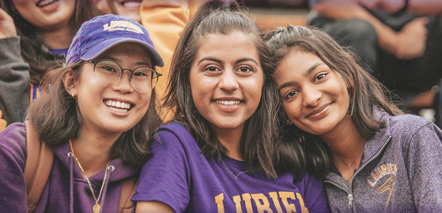 Three Laurier students at the football stadium