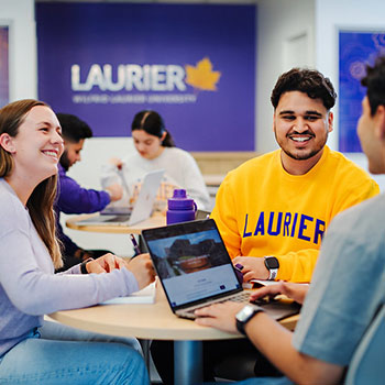 three smiling students sitting inside of Laurier Milton