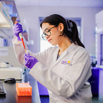Student in a lab wearing safety glasses and a lab coat
