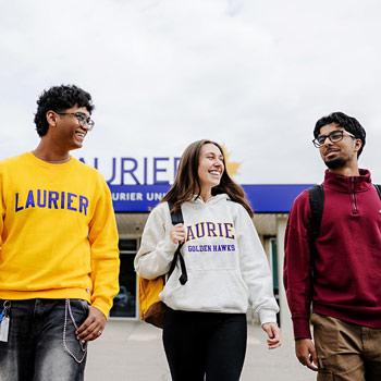 three students walking outside of laurier milton in the fall