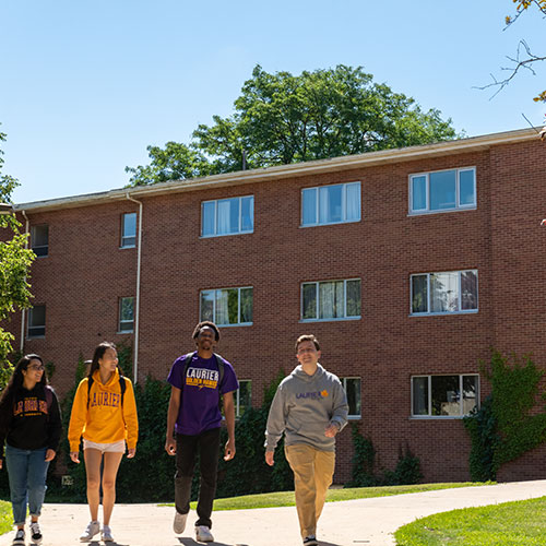 Four students walking in front of residence building