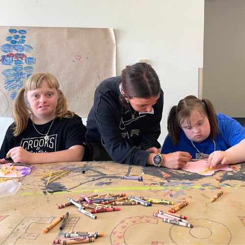 A woman and two girls are colouring.